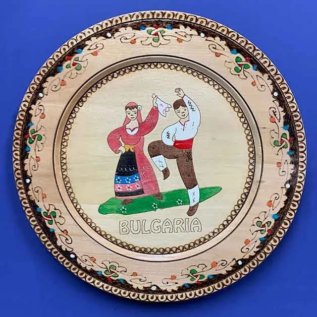 Plato decorativo de madera pintado a mano de Bulgaria, con bailarines folclóricos tradicionales con trajes de colores, regalado al Dr. Arturo Bonilla como muestra internacional de aprecio de la familia de un paciente que se sometió a cirugía de microtia