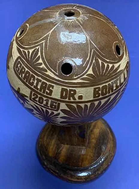 Ocarina de calabaza tallada a mano y esmaltada, grabada con «Gracias Dr. Bonilla 2016» y rodeada de intrincados motivos florales: un extraordinario regalo artesanal de agradecimiento en español al Dr. Arturo Bonilla de un paciente agradecido que se sometió a cirugía de microtia