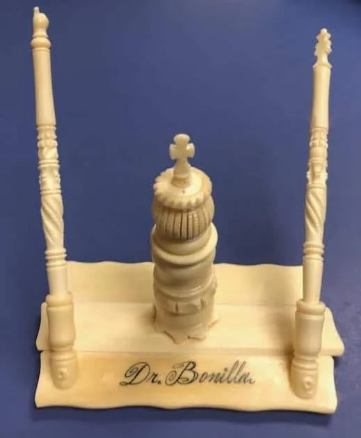 Portalápices de tono marfil tallado con gran detalle, con columnas ornamentadas y una torre central grabada con Dr. Bonilla: un elaborado regalo artesanal de agradecimiento al Dr. Arturo Bonilla de un paciente agradecido que se sometió a cirugía de microtia