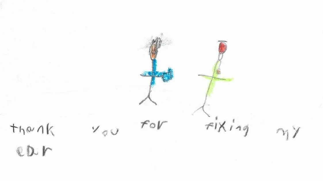 Dibujo minimalista con crayones de un niño muy pequeño, con dos figuras de palitos de colores y las palabras escritas a mano «gracias por arreglarme la oreja»: una expresión sencilla y pura de gratitud al Dr. Arturo Bonilla de un paciente joven que se sometió a cirugía de microtia