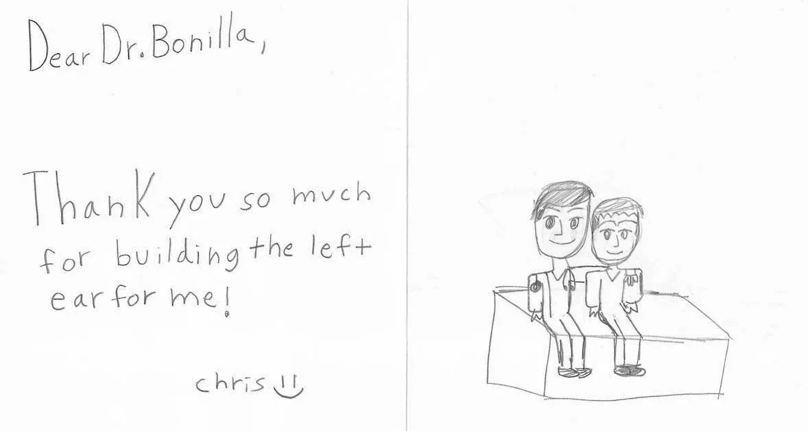 Nota y dibujo a lápiz de un niño llamado Chris, que agradece al Dr. Arturo Bonilla haberle construido la oreja izquierda, acompañados de un cuidadoso boceto a lápiz de dos figuras sentadas una junto a la otra: un regalo cálido y personal de un paciente agradecido que se sometió a cirugía de microtia