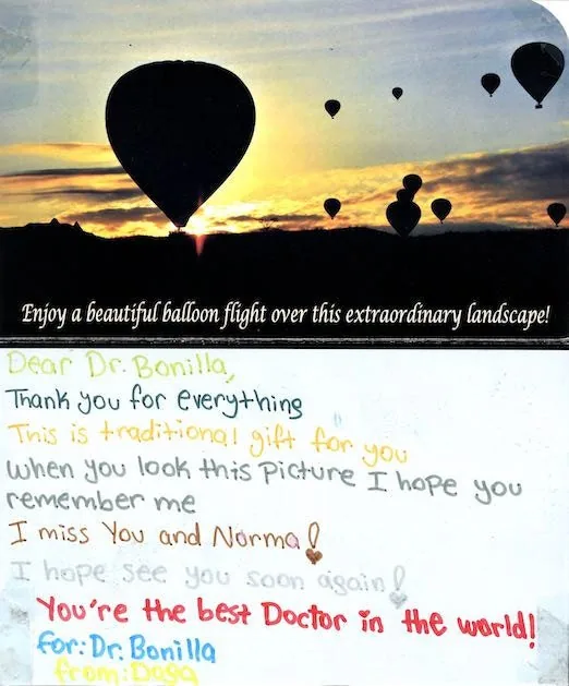 Postal de un paisaje con globos aerostáticos, de un paciente llamado Doga, que declara al Dr. Arturo Bonilla el mejor doctor del mundo y expresa una profunda gratitud tras la cirugía de microtia: un preciado regalo de agradecimiento de un paciente agradecido que se sometió a reconstrucción por microtia