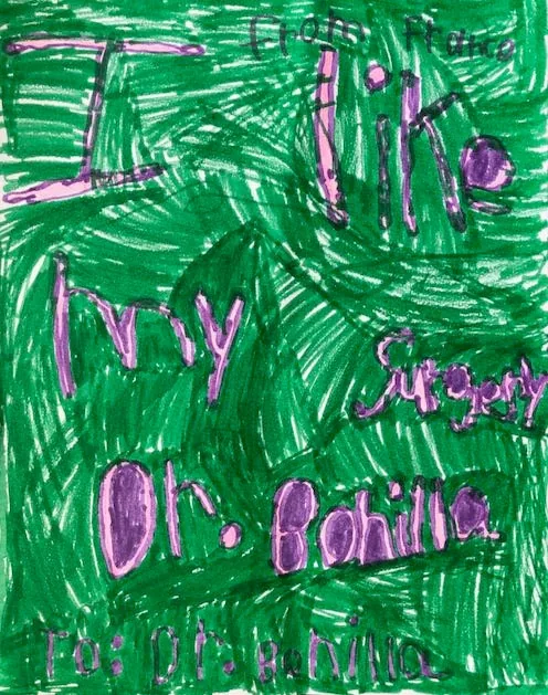 Dibujo con crayones de intensos colores verde y morado de un paciente de Francia, con las palabras «Me gusta mi cirugía, Dr. Bonilla» escritas por todo el dibujo: un expresivo regalo internacional de agradecimiento al Dr. Arturo Bonilla de un paciente agradecido que se sometió a cirugía de microtia