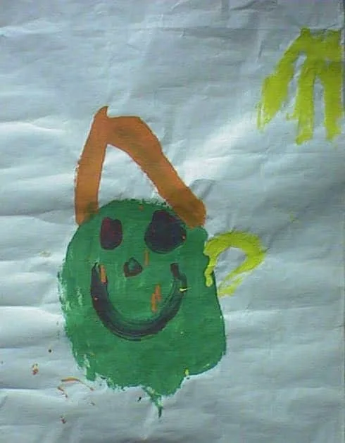 Pintura infantil hecha con los dedos sobre papel blanco, que muestra una cara sonriente verde con un arco naranja y una huella de mano amarilla: un regalo alegre e inocente de agradecimiento al Dr. Arturo Bonilla de un paciente muy pequeño y agradecido que se sometió a cirugía de microtia