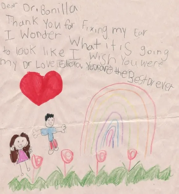 Carta de agradecimiento de Elicia al Dr. Bonilla, con un gran corazón rojo, un arcoíris de colores y flores rosas sobre césped verde