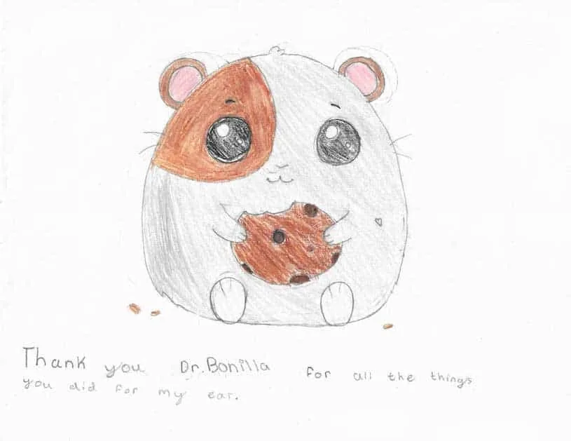 Dibujo detallado a lápiz de un hámster redondo de ojos grandes comiendo una galleta con chispas de chocolate, con una nota manuscrita que agradece al Dr. Arturo Bonilla todo lo que hizo por la oreja del paciente: un encantador regalo artístico de un paciente agradecido que se sometió a cirugía de microtia