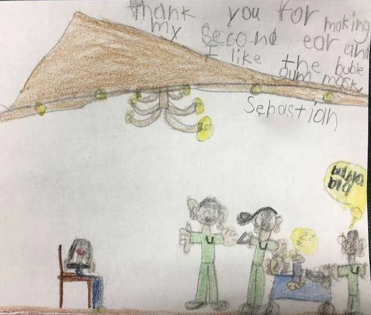 Dibujo infantil a lápiz de Sebastian, que representa una escena de cirugía bajo un techo parecido a una tienda de campaña, con una nota escrita a mano que agradece al Dr. Arturo Bonilla haberle hecho su segunda oreja y señala que lo que más le gustó fue el chicle: un regalo imaginativo de agradecimiento de un paciente agradecido que se sometió a cirugía de microtia