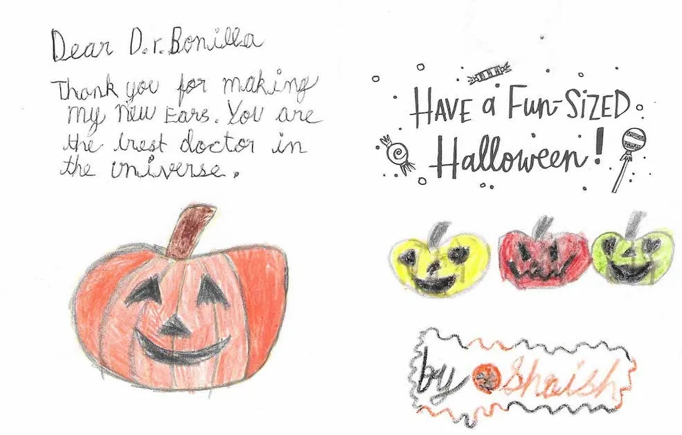 Tarjeta de Halloween de un niño llamado Shaish, con calabazas de Halloween dibujadas con crayones y el mensaje de que el Dr. Arturo Bonilla es el mejor doctor del universo por hacer nuevas orejas: un alegre regalo de agradecimiento de un paciente agradecido que se sometió a cirugía de microtia