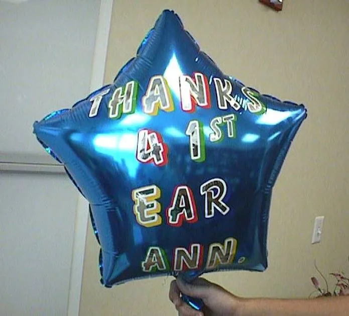 Globo brillante de mylar azul en forma de estrella, rotulado a mano con una abreviatura de «Gracias por el 1.er aniversario de la oreja»: un festivo regalo de agradecimiento al Dr. Arturo Bonilla para celebrar el primer aniversario de la oreja de un paciente después de la cirugía de reconstrucción por microtia