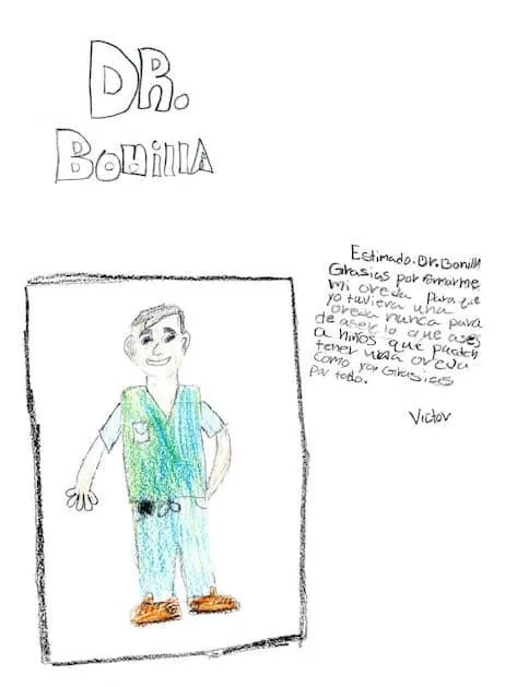 Dibujo infantil con crayones del Dr. Arturo Bonilla con ropa quirúrgica, acompañado de una carta en español de un paciente llamado Victor, que expresa gratitud por su cirugía de oreja y su esperanza de que el doctor siempre ayude a niños como él: un emotivo regalo bilingüe de agradecimiento de un paciente agradecido que se sometió a cirugía de microtia