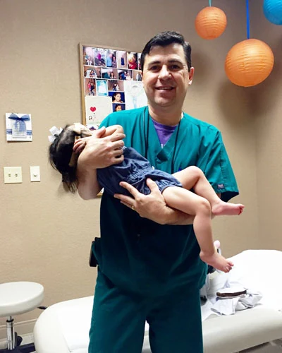 Dr. Arturo Bonilla, pediatric microtia surgeon in San Antonio, holds a newborn infant with microtia during an early consultation at his office, emphasizing the importance of early hearing intervention from birth.